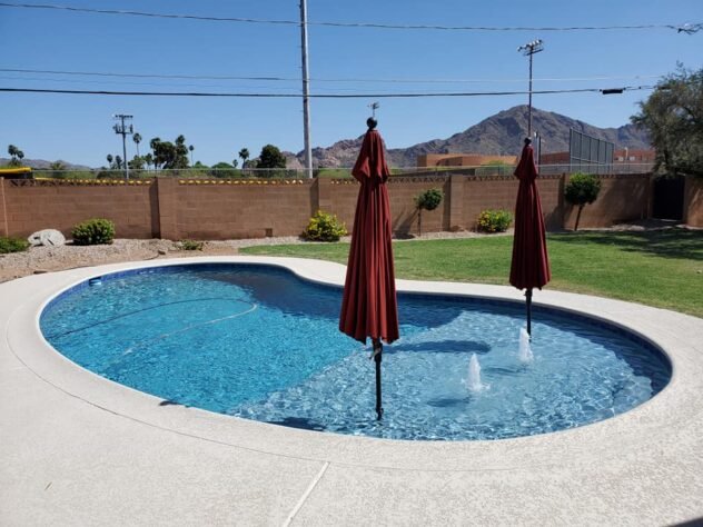 Resurfaced backyard swimming pool with a new blue pebble finish in Mesa, AZ