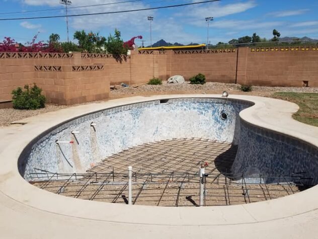 Drained swimming pool with damaged interior removed before resurfacing